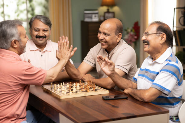 senior people giving high five after winning chess at home