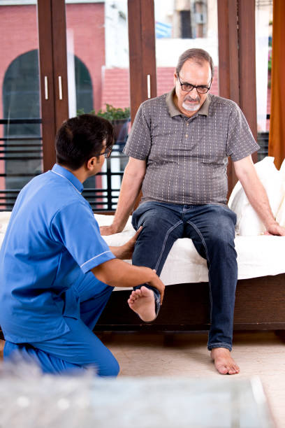 physiotherapist giving leg therapy to old man on bed
